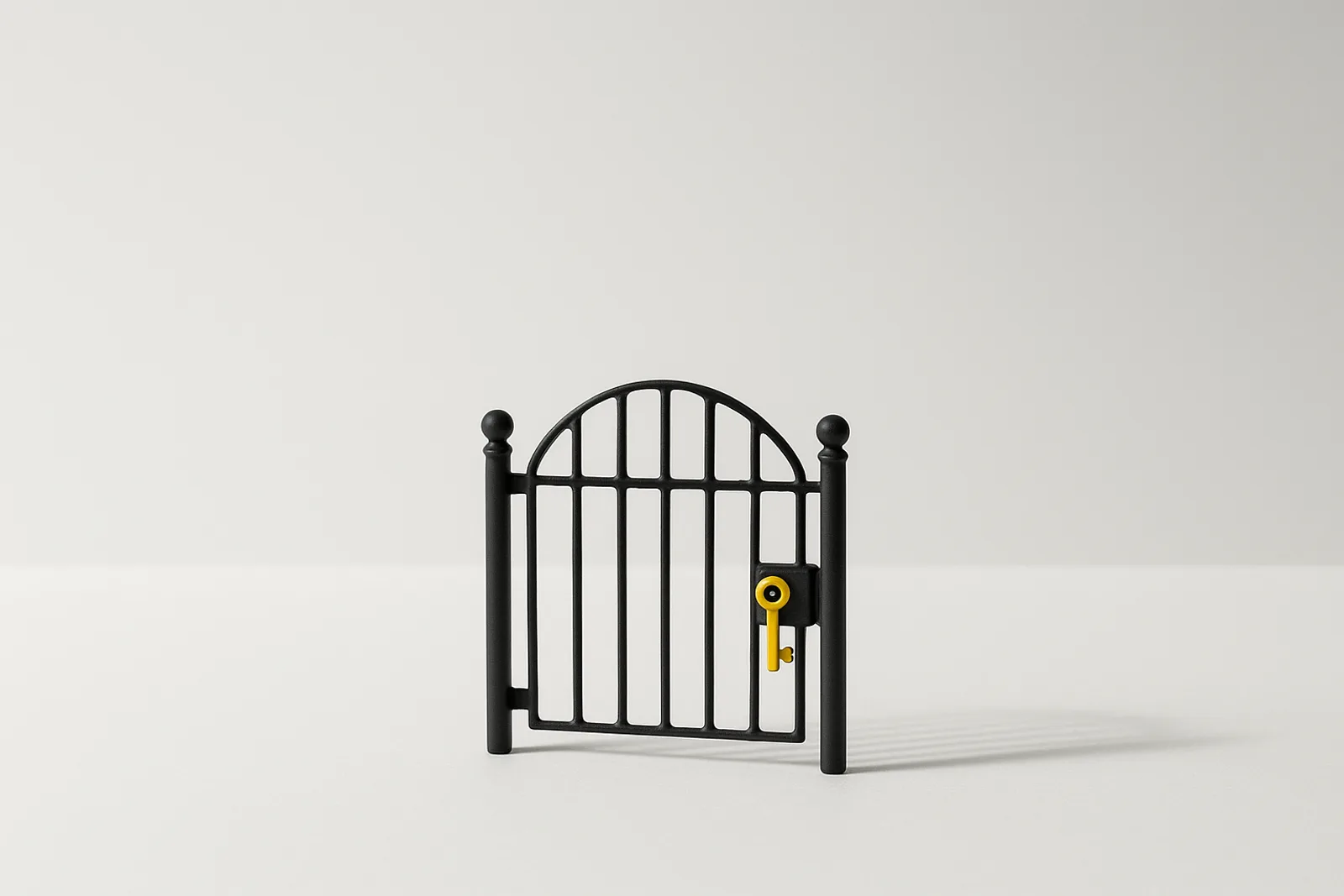 A matte black wrought iron gate standing closed on clean white, with one lemon-yellow key left in its lock, the way in that nobody decided to close.